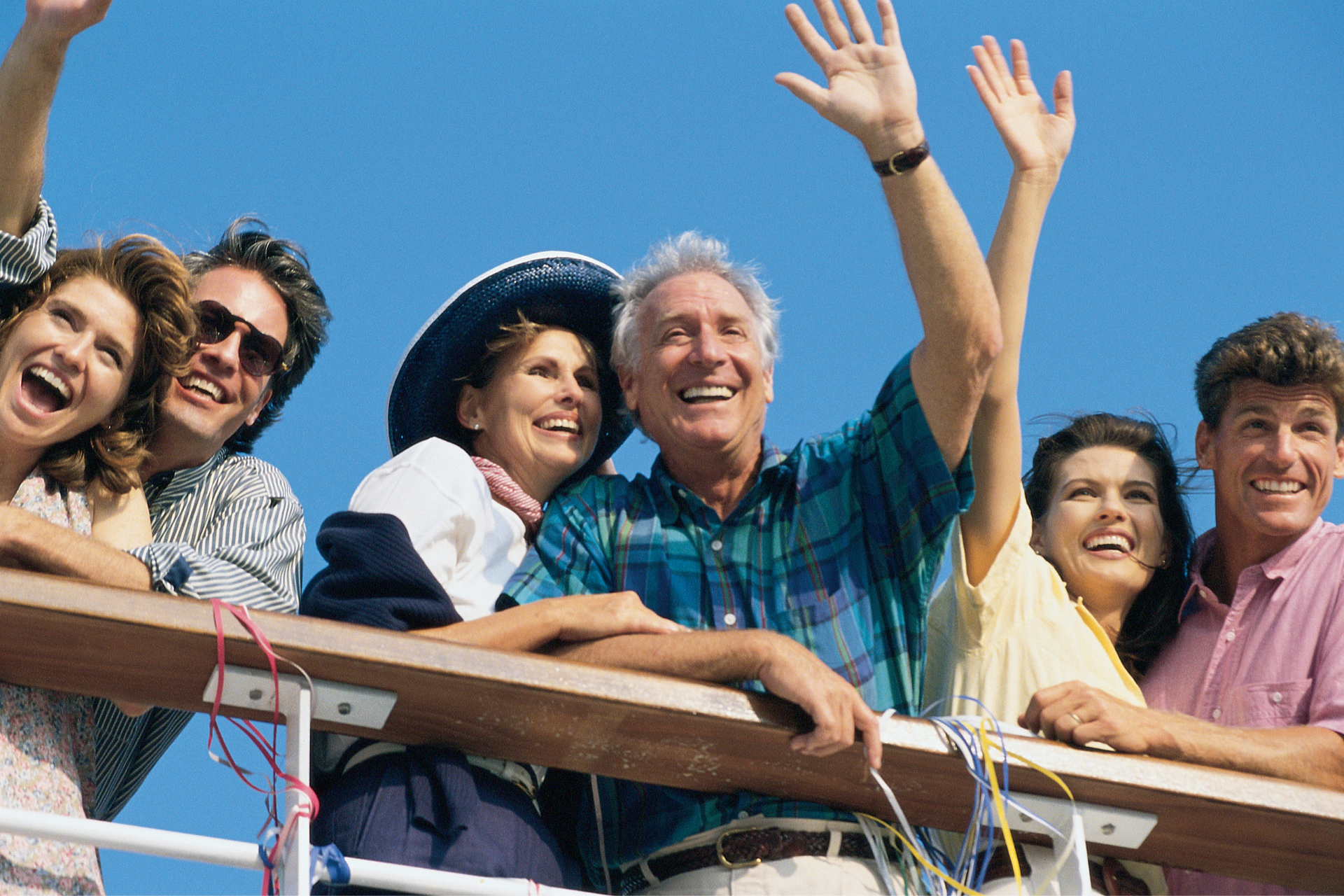 happy couples waving from the deck of a cruise ship