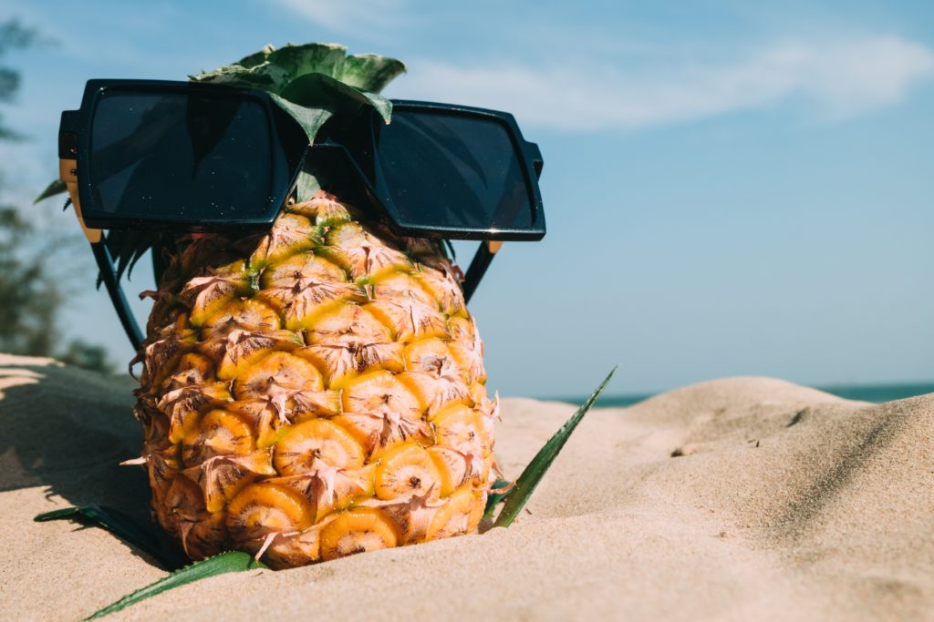 pineapple on the beach wearing sunglasses